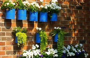 Pots de fleurs suspendus en métal bleu fixés au mur d’un balcon, créant une décoration verticale colorée et pratique pour optimiser l’espace extérieur.