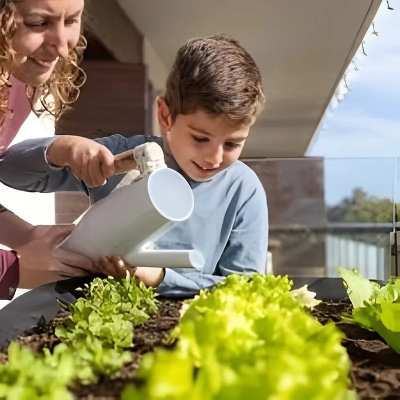 Moment de complicité entre un adulte et un enfant arrosant ensemble un potager de balcon avec des salades vertes.