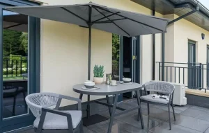 Demi-parasol mural gris grande envergure, fixé directement au mur pour libérer totalement le sol d'un balcon de taille adaptée.