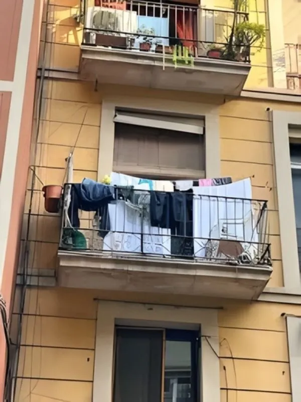 Balcon encombré avec linge visible depuis la rue.