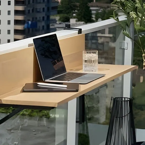 Table de balcon suspendue en bois clair avec ordinateur portable et tablette, aménagement petit espace bureau extérieur.