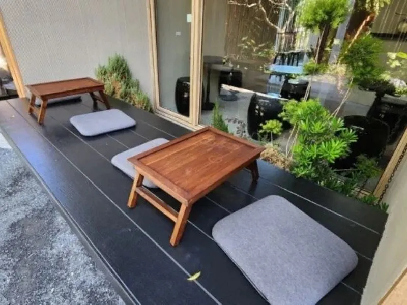 Espace de méditation sur un petit balcon avec coussin de sol, table en bois et service à thé japonais.