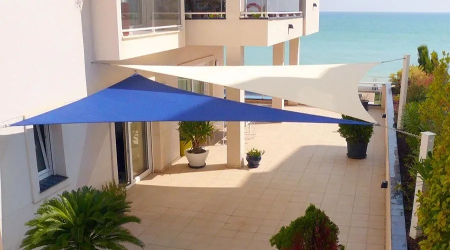 Comparatif de voiles d'ombrage triangulaires bleue et blanche installées sur un balcon moderne.