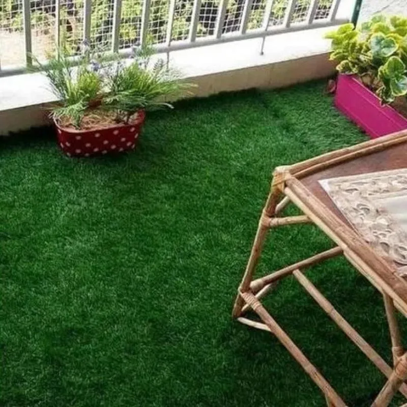 Revêtement de sol en gazon synthétique pour petit balcon avec mobilier de jardin en bois.